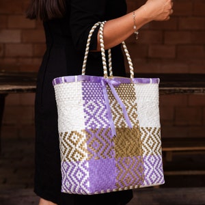 Handwoven Artisan Bag made of recycled plastic in white, lilac and gold tones with lilac ribbon details.