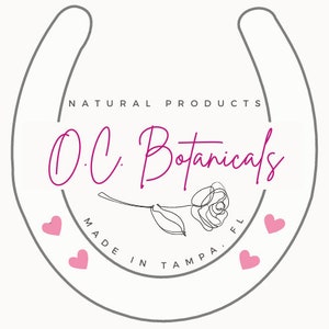 May include: A gray horseshoe with the text "NATURAL PRODUCTS O.C. Botanicals MADE IN TAMPA, FL" in a pink cursive font. A pink rose with a stem and leaves is inside the horseshoe. There are five pink hearts around the horseshoe.