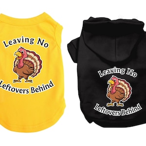 Puede incluir: Dos camisetas para perros con temática de Acción de Gracias. Una es amarilla con un diseño sin mangas y la otra es negra con capucha. Ambas camisetas presentan un pavo de dibujos animados y el texto "Leaving No Leftovers Behind".