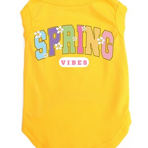 May include: Yellow sleeveless dog shirt with the text "SPRING VIBES" in rainbow colors with white flowers around the text.