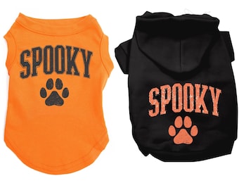 May include: Two pet shirts, one orange and one black. The orange shirt has the word "SPOOKY" in black block letters and a black paw print. The black shirt has the word "SPOOKY" in orange block letters and an orange paw print.