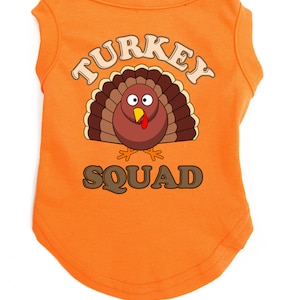 May include: Orange sleeveless dog shirt with a cartoon turkey graphic and the text "TURKEY SQUAD".