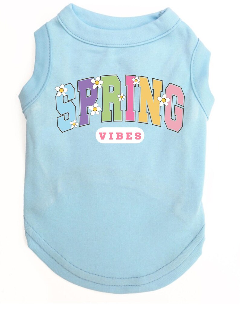 May include: Light blue sleeveless dog shirt with a rainbow colored "SPRING VIBES" graphic with white daisy accents.