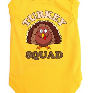 May include: Yellow sleeveless dog shirt with a cartoon turkey graphic and the text "TURKEY SQUAD".