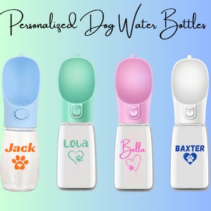 May include: Four personalized dog water bottles in blue, green, pink, and white. Each bottle has a matching colored drinking bowl and a clear water reservoir. The bottles are labeled with dog names and paw print designs.