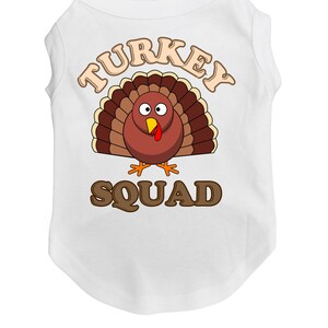 May include: White sleeveless dog shirt with a brown cartoon turkey and the text "TURKEY SQUAD" in brown letters.