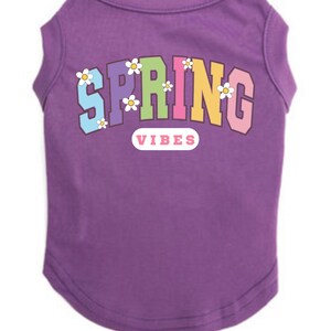 May include: Purple sleeveless dog shirt with the text "SPRING" in rainbow colors and white flowers. The text "VIBES" is below the word "SPRING" in a pink rectangle.