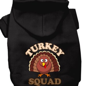May include: Black hooded dog sweater with a brown cartoon turkey graphic and the text "TURKEY SQUAD".