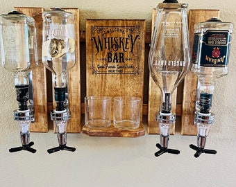 May include: Wooden wall mounted whiskey bar with four liquor bottle dispensers, two shot glasses, and a sign that reads "Welcome to Whiskey Bar, Good Friends Good Drinks Great Times".