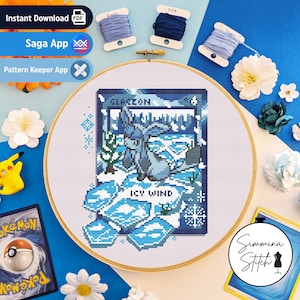 May include: A cross-stitch pattern of Glaceon, an ice-type Pokemon, with the text "ICY WIND" and "GLACEON" on a blue and white background. The pattern is in a wooden embroidery hoop.