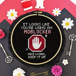 Puede incluir: Aro de bordado negro con el texto "IT LOOKS LIKE YOU'RE USING AN ADBLOCKER" y una señal de stop roja con una huella de mano blanca. El texto debajo de la señal de stop dice "NICE WORK, KEEP IT UP."