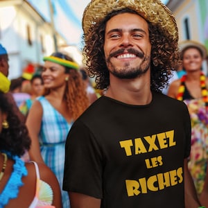 May include: A person wearing a black t-shirt with the text "TAXEZ LES RICHES" in yellow letters. The person is smiling and wearing a straw hat.