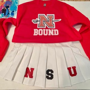 May include: A red sweatshirt with a white N and a white sword, with the word BOUND underneath. A white pleated skirt with the letters NSU in red, black, and red glitter.