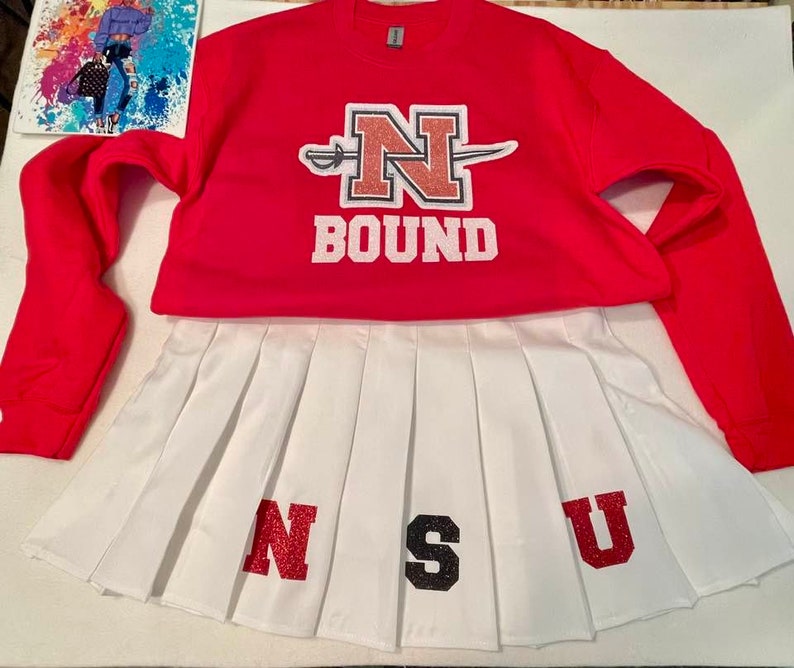 May include: A red sweatshirt with a white N and a white sword, with the word BOUND underneath. A white pleated skirt with the letters NSU in red, black, and red glitter.