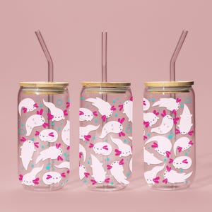 May include: Three clear glass tumblers with bamboo lids and pink and white axolotl illustrations. Each tumbler has a clear plastic straw.