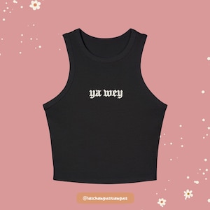 K&ouml;nnte beinhalten: Schwarzes geripptes Tanktop mit dem Text "ya wey" in wei&szlig;er gotischer Schrift. Das Top ist &auml;rmellos mit einem runden Ausschnitt. Der Hintergrund ist einfarbig rosa mit wei&szlig;en Blumen- und Punktakzenten.