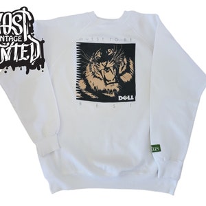 May include: White sweatshirt with a black and white graphic of a tiger with the text "QUEST TO BE BEST DELL" printed on the front.