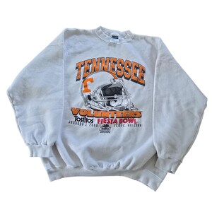 May include: A white sweatshirt with the word "Tennessee" in orange block letters above a football helmet graphic. Below the helmet, the text reads "Volunteers" and "Tostitos Fiesta Bowl January 2, 2000, Tempe, Arizona."
