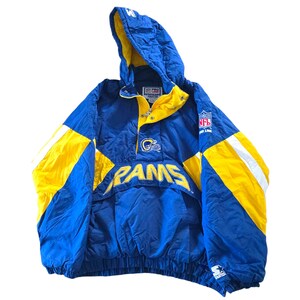 May include: Blue and yellow Los Angeles Rams Starter jacket with a hood. The jacket features the team name "RAMS" across the front, along with the NFL logo and team emblem. The jacket has a drawstring at the bottom and a snap closure.