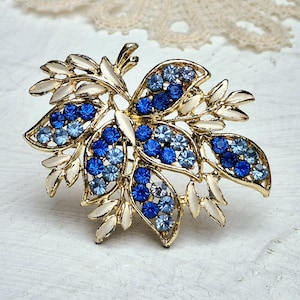 Wunderschöne Vintage große goldfarbene Blattbrosche mit weißer Emaille und blauen Strasssteinen