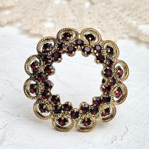 Beautiful Vintage Round Openwork Brooch in Gold tone with Garnet Glass Rhinestones.