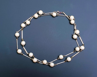 Elegante collar largo de una sola hebra con palos en tono plateado vintage y perlas sintéticas.