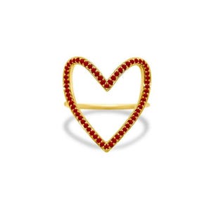 May include: A gold-colored ring in the shape of a heart, outlined with small red gemstones. The ring is set against a white background, highlighting the jewelry's design and color.