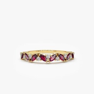 May include: A delicate gold band ring with a row of marquise-shaped ruby and round diamond stones.