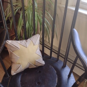 May include: A black wooden rocking chair with a yellow star-shaped pillow on the seat. The chair has a painted design on the back.