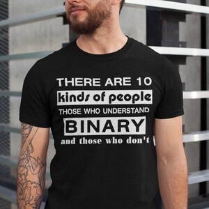 May include: Black t-shirt with white text. The text reads: "THERE ARE 10 kinds of people, those who understand BINARY and those who don't." The shirt is a crew neck style.