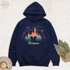 May include: A navy blue hoodie with a vintage-style graphic of a rainbow-colored castle with fireworks and the text "BARBARA" underneath. The castle is a silhouette of the iconic Disney castle.