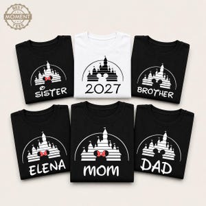 Puede incluir: Una colecci&oacute;n de camisetas negras y blancas con un dise&ntilde;o de castillo. Las camisetas presentan textos como "Sister", "Brother", "Mom", "Dad", "Elena" y "2027". El dise&ntilde;o del castillo incluye un lazo de Minnie Mouse. Las camisetas est&aacute;n dispuestas sobre una superficie clara.