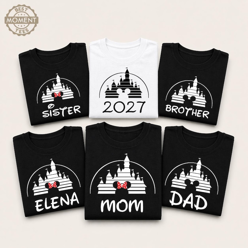 Puede incluir: Una colecci&oacute;n de camisetas negras y blancas con un dise&ntilde;o de castillo. Las camisetas presentan textos como "Sister", "Brother", "Mom", "Dad", "Elena" y "2027". El dise&ntilde;o del castillo incluye un lazo de Minnie Mouse. Las camisetas est&aacute;n dispuestas sobre una superficie clara.
