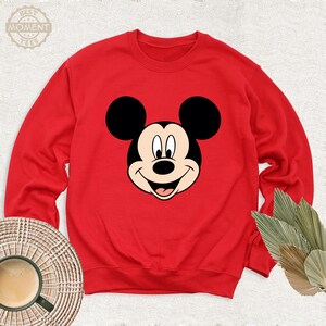 May include: Red sweatshirt featuring a black and white cartoon image of Mickey Mouse on the front.