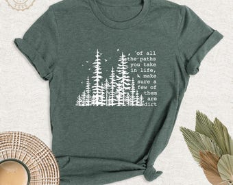 May include: A dark green short-sleeved t-shirt featuring a white graphic of a forest of pine trees and the text: Of all the paths you take in life, make sure a few of them are dirt. The shirt has a crew neckline and a standard fit.