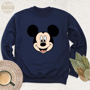 May include: A navy blue sweatshirt featuring a cartoon image of Mickey Mouse's face.