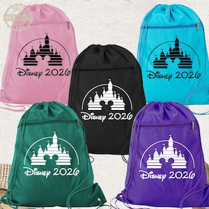 May include: Five drawstring backpacks in pink, black, turquoise, dark green, and purple. Each bag features a front zipper pocket and a graphic of a castle silhouette with a mouse head icon and the text Disney 2026 printed in a contrasting color.