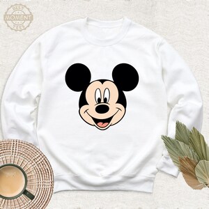 May include: White sweatshirt featuring a cartoon image of Mickey Mouse's face.