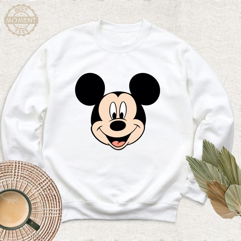 May include: White sweatshirt featuring a cartoon image of Mickey Mouse's face.