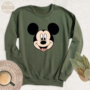 May include: A green sweatshirt featuring a cartoon image of Mickey Mouse on the front.