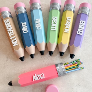May include: Seven pencil-shaped containers in various pastel colours, each featuring a silver-coloured band, a pink eraser top, and a black tip. Six are upright, personalised with white raised lettering: NO.1 TEACHER, Oliver, Olivia, Lucas, Hudson, and Emma. One pink container labelled Alexa lies horizontally, filled with standard pencils.