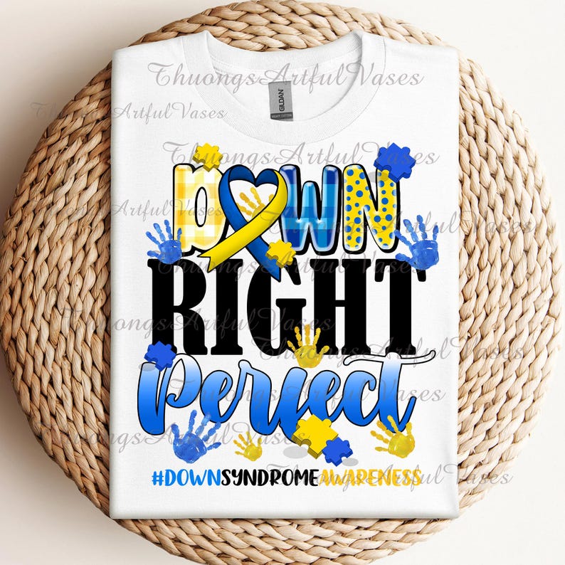 May include: White t-shirt with a blue and yellow graphic that says "Down Right Perfect" with handprints and a yellow ribbon. The hashtag #DownSyndromeAwareness is at the bottom of the graphic.
