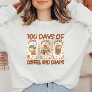 May include: White sweatshirt with the text "100 Days of Coffee and Chaos" in brown and orange. The design includes a globe, books, and a coffee cup. The sweatshirt is a long-sleeved crew neck.
