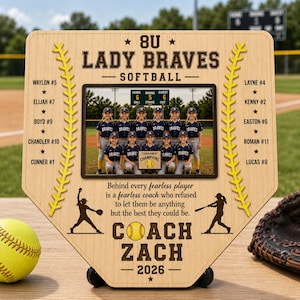 Könnte beinhalten: Baseballförmige Holzplakette mit einem Teamfoto der 8U Lady Braves Softballmannschaft. Die Plakette enthält den Teamnamen, den Namen des Trainers und das Jahr. Das Design beinhaltet Baseballnähte und Spielersilhouetten.