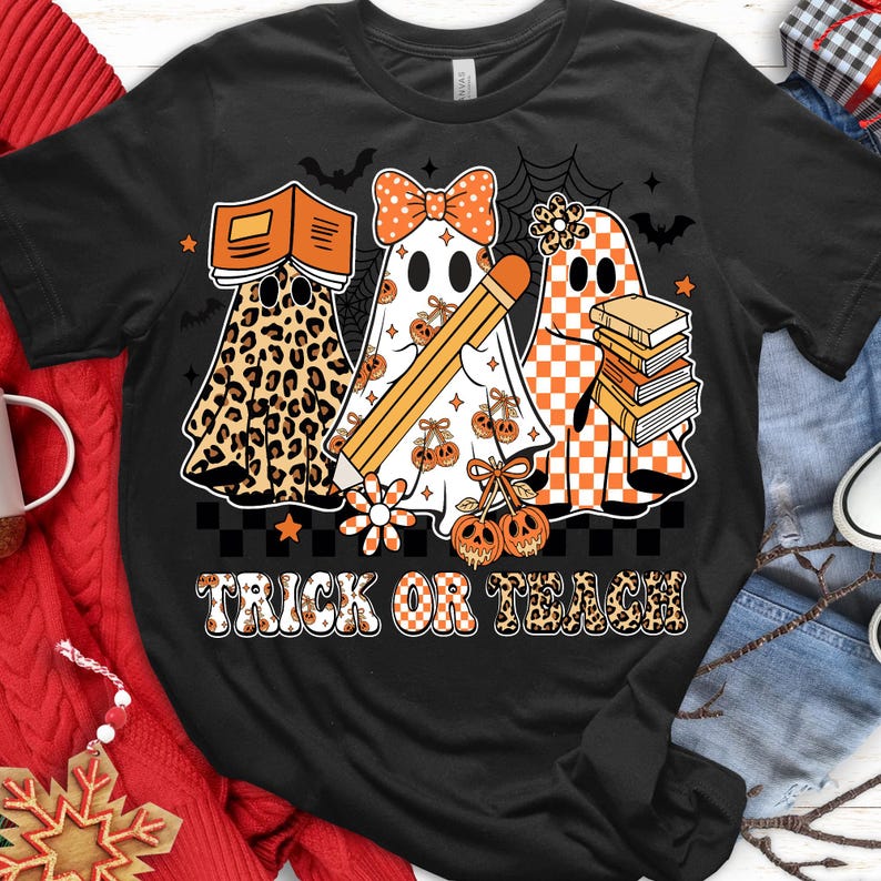 May include: Black t-shirt with a Halloween-themed design. Features three ghost figures, one with a leopard print, one with a bow and pencil, and one with a checkered pattern. The text "TRICK OR TEACH" is displayed in a decorative font.
