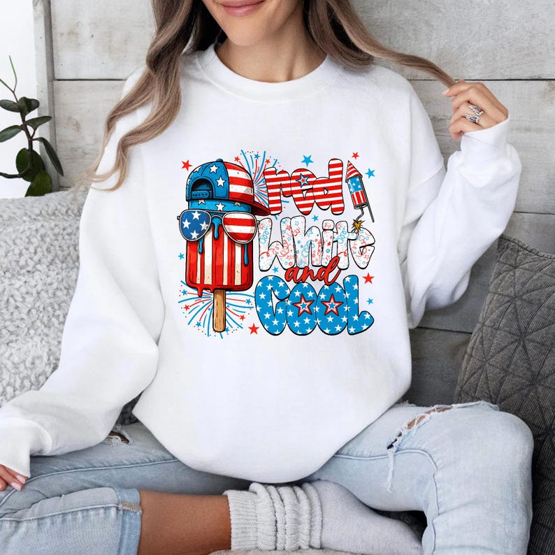 May include: White sweatshirt with a patriotic design featuring a popsicle wearing sunglasses and a baseball cap, with the text "Red, White, and Cool". The design incorporates red, white, and blue colors, fireworks, and stars.