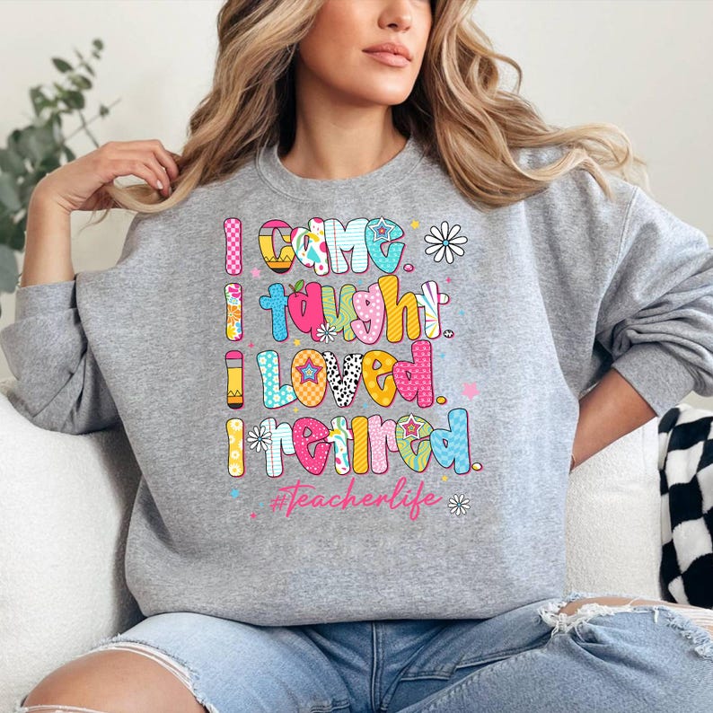 May include: A gray sweatshirt with the words "I CAME, I TAUGHT, I LOVED, I RETIRED" in colorful, patterned letters. The text includes the hashtag #Teacherlife and floral accents. The sweatshirt is a casual style.