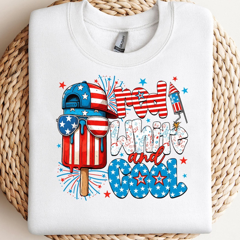 May include: White sweatshirt with a patriotic popsicle graphic. The popsicle wears a hat and sunglasses, both in red, white, and blue. Text reads "Red, White, and Cool" with star accents, celebrating Independence Day.