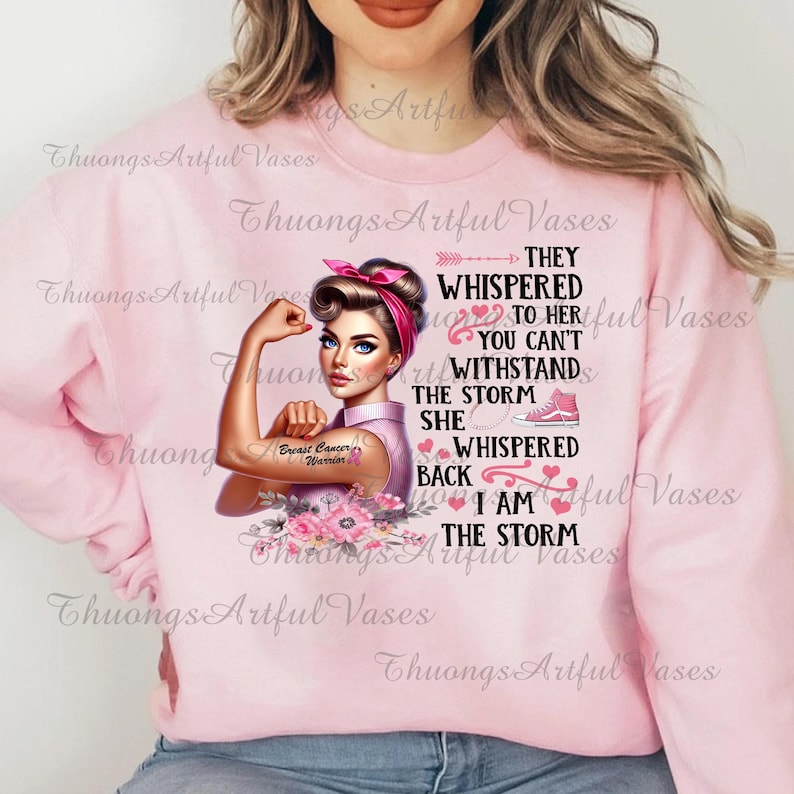 Puede incluir: Sudadera rosa con un gr&aacute;fico de una mujer con un brazo fuerte y el texto "They whispered to her you can't withstand the storm she whispered back I am the storm". El gr&aacute;fico tambi&eacute;n incluye una cinta rosa y las palabras "Breast Cancer Warrior".