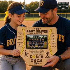 May include: A wooden baseball home plate-shaped plaque featuring a team photo and text. The plaque reads "8U Lady Braves Softball" and includes player names and coach information. The team is wearing navy blue and white uniforms.